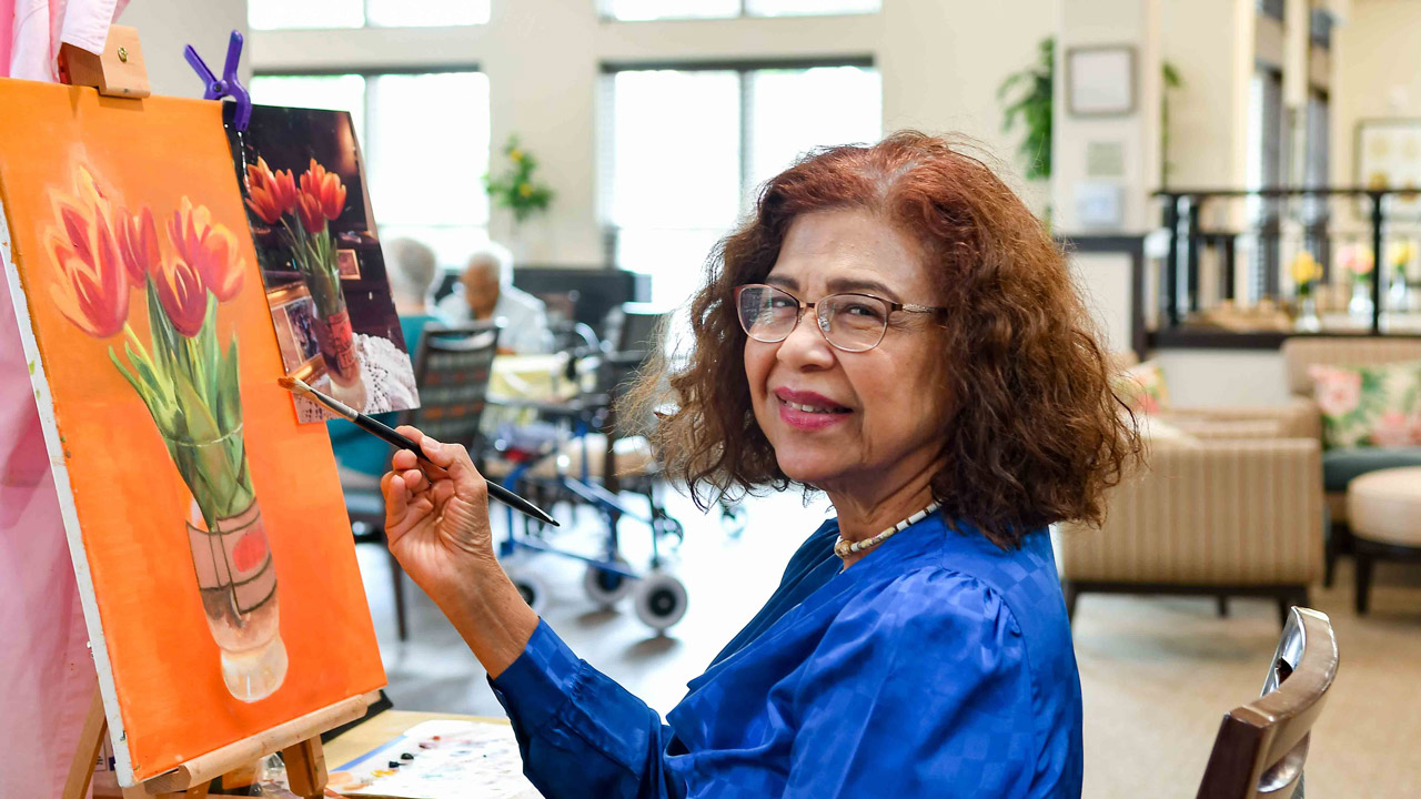 A resident painting during an art activity at Willow Creek