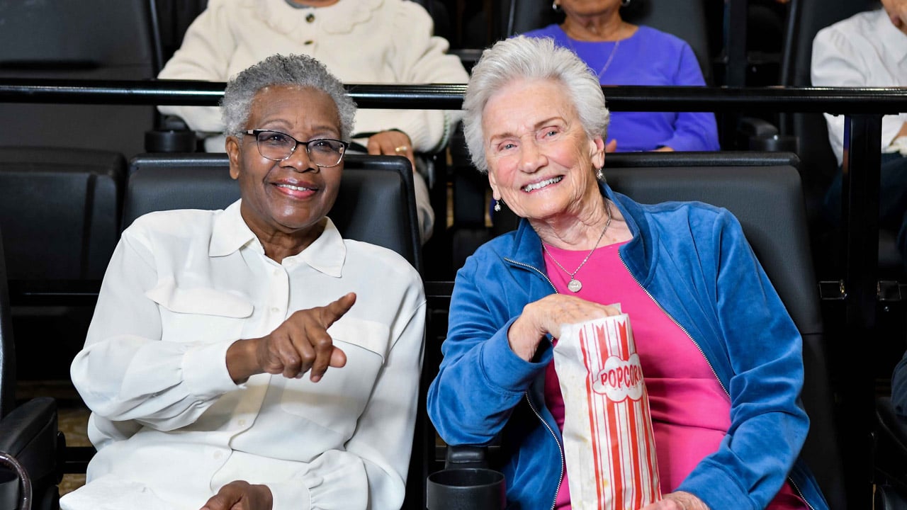 Two residents watching a film in the Willow Creek theater