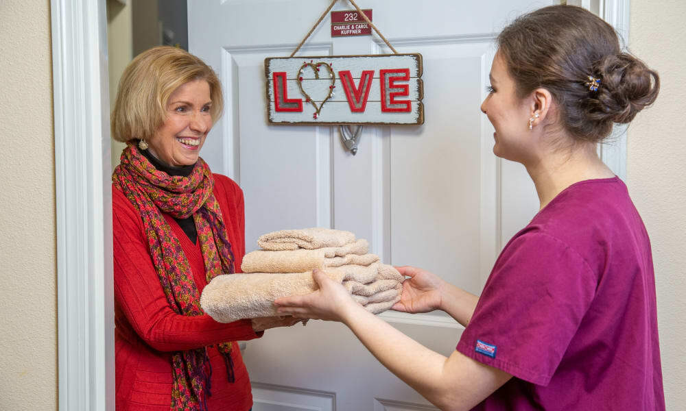 A team member delivering fresh linens to a resident at Willow Creek